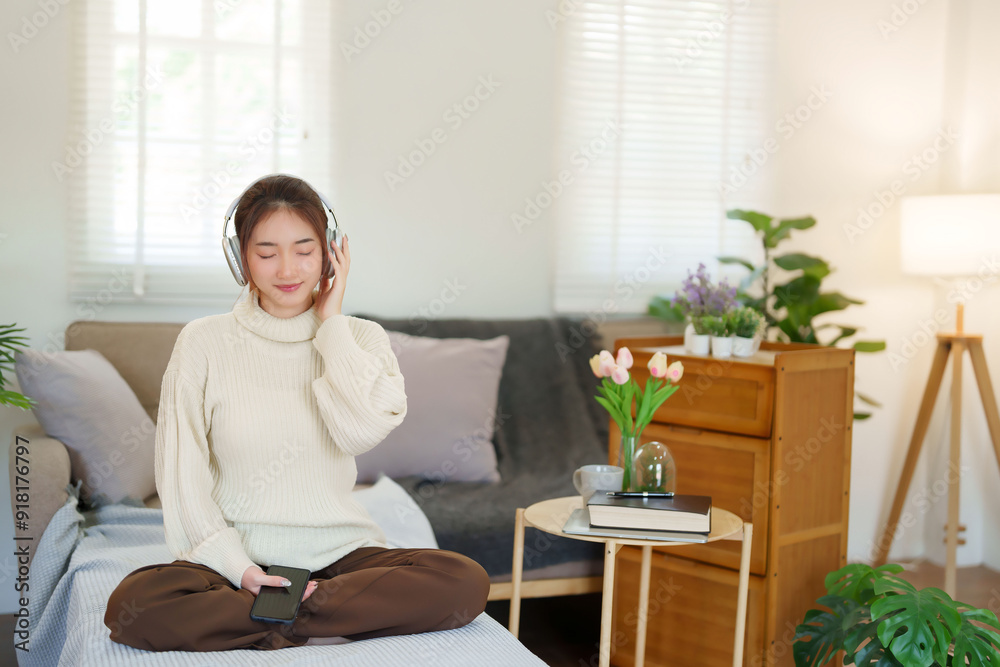 Young asian women in sweater wear headphone and close eyes to listening music with happiness while sitting on couch to relaxation and doing activity for spending time with slow life lifestyle at home Young asian women in sweater wear headphone and close eyes to listening music with happiness while sitting on couch to relaxation and doing activity for spending time with slow life lifestyle at home