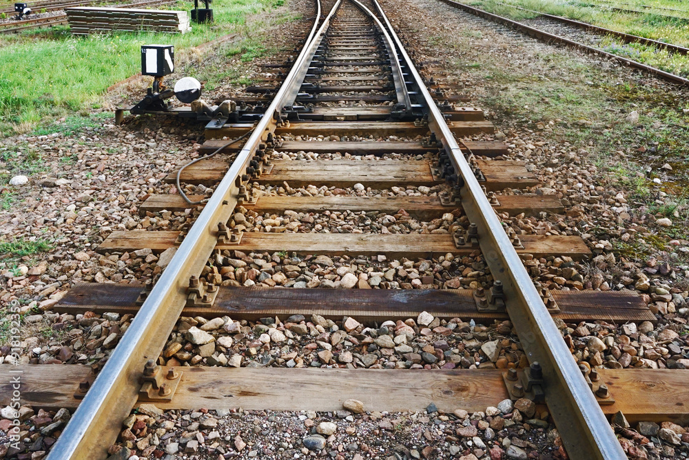 Railway background. Train track texture. Steel rail on gravel. Train tracks with a side-mounted switch mechanism cargo trail. Old railroad wooden tie. Junction where tracks split. Railway background. Train track texture. Steel rail on gravel. Train tracks with a side-mounted switch mechanism cargo trail. Old railroad wooden tie. Junction where tracks split.