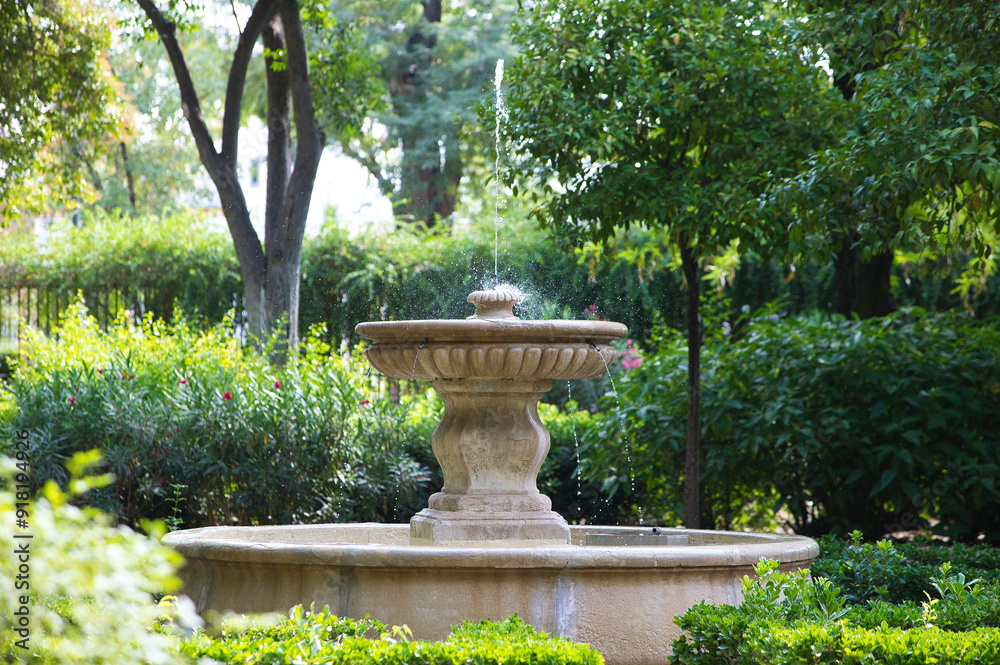 Stone fountain surrounded by green vegetation in a park in Seville, Spain. Stone fountain surrounded by green vegetation in a park in Seville, Spain.