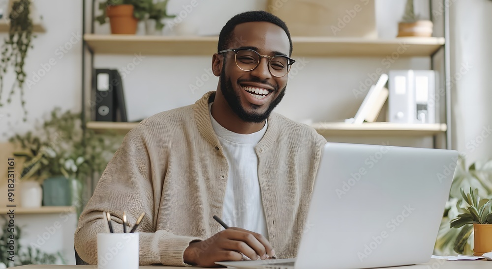 A young happy man sits at his desk with a laptop,workspace A young happy man sits at his desk with a laptop,workspace