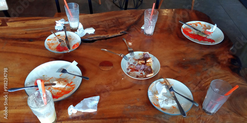 Фотография The leftover food and dirty empty dishes on the restaurant table.