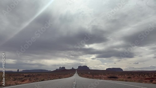 The iconic Monument Valley road from Forrest Gump Point in Utah, USA. Taken on a cloudy, hazy day with an atmospheric mood. Symbolic of the wild west and desert road trips. photo