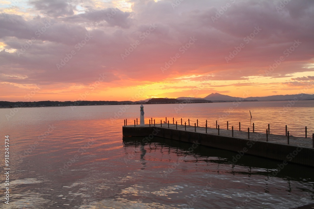 Obraz premium Lighthouse at Sunset with Colorful Sky and Lake Reflection in Japan