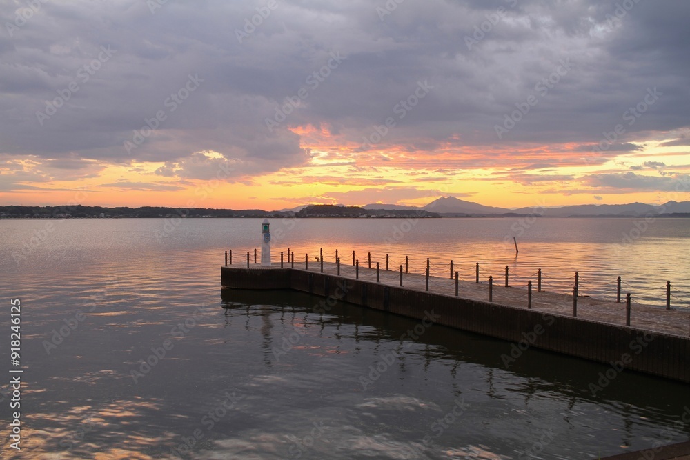 a lighthouse with colorful sky and reflection on lake during sunset with far view of mountains a lighthouse with colorful sky and reflection on lake during sunset with far view of mountains
