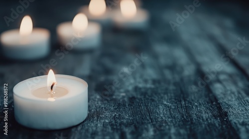 A serene photograph featuring several small tealight candles emitting a warm and calming glow in a darkened space, creating a peaceful and meditative atmosphere of tranquility and reflection.