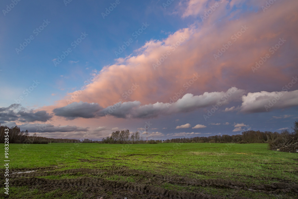 Golden hues stretch across the horizon as soft clouds dance above a lush green landscape during a tranquil twilight moment. Golden hues stretch across the horizon as soft clouds dance above a lush green landscape during a tranquil twilight moment.