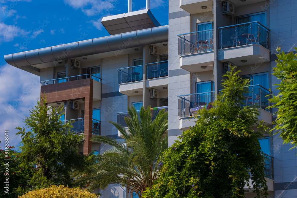 Obraz premium City view on a sunny day. Modern building and houses against the blue sky.