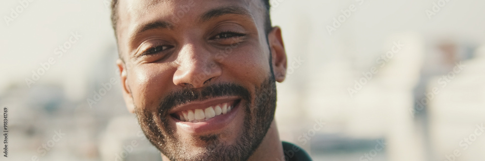 Fototapeta premium Close-up, Young man sitting in the harbor with yachts on the background, looking at the camera and smiling