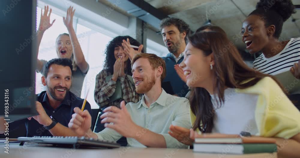 Multi-ethnic group of people at work. Looking patiently at screen. Waiting for important moment. After seeing positive result everyone exclaiming. Clapping their hands while smiling with joy.
