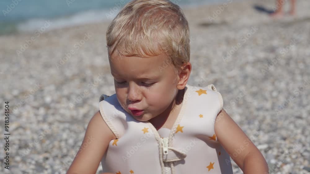 Happy little boy in swim vest life jacket playing on summer beach swimming in sea. Cute child in float lifejacket learning to swim in water. Yevpatoriya, Crimea, Russia 2024 Happy little boy in swim vest life jacket playing on summer beach swimming in sea. Cute child in float lifejacket learning to swim in water. Yevpatoriya, Crimea, Russia 2024