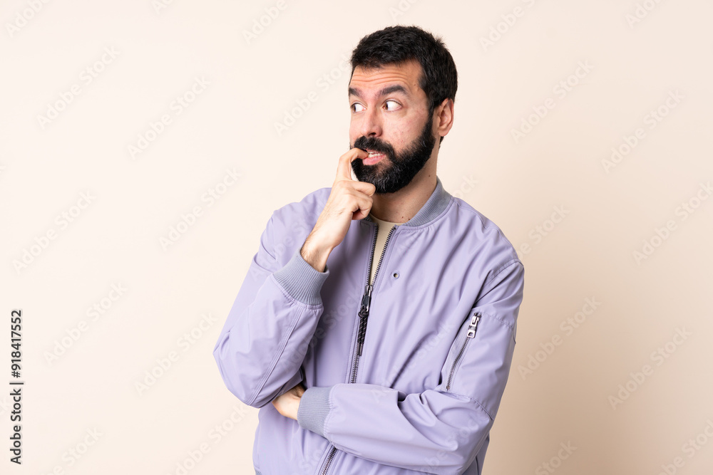 Caucasian man with beard wearing a jacket over isolated background nervous and scared Caucasian man with beard wearing a jacket over isolated background nervous and scared