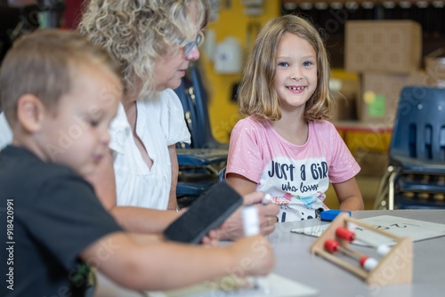 A teacher is helping a child with a math problem. The teacher is reviewing the students work in the classroom setting.