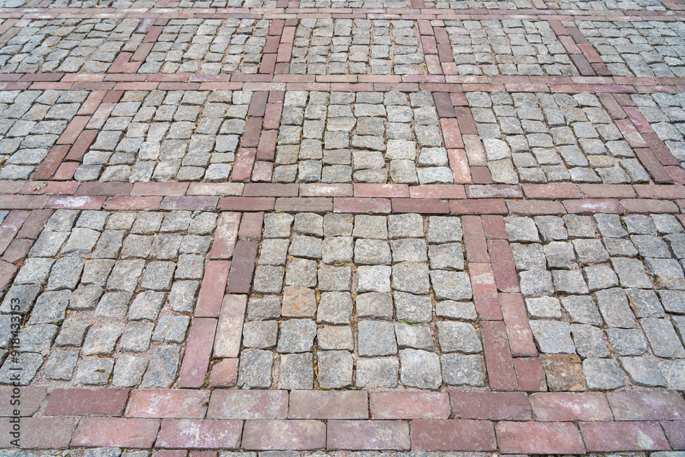 Fototapeta premium Cobblestone pavement with red brick pattern, geometric design, weathered stones, rustic outdoor setting