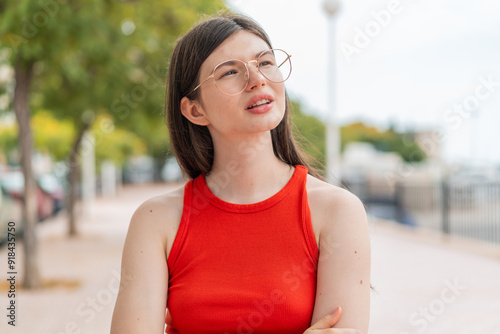 Young woman with glasses at outdoors with confuse face expression photo