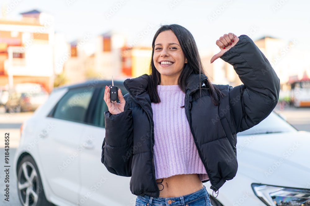 Fototapeta premium Young woman at outdoors holding car keys at outdoors proud and self-satisfied