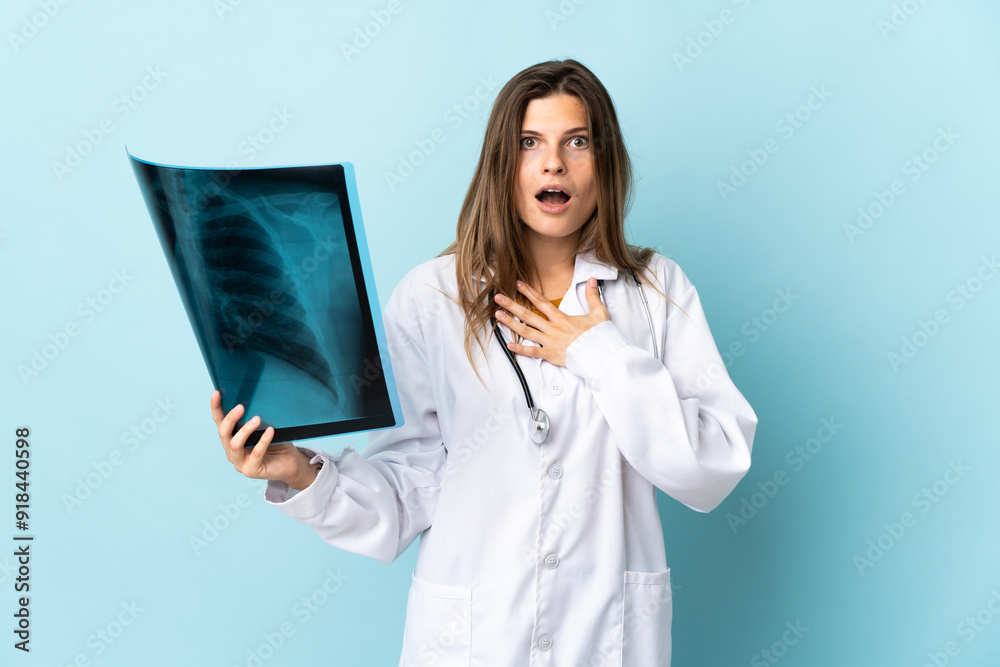 Young doctor woman holding radiography over isolated background surprised and shocked while looking right Young doctor woman holding radiography over isolated background surprised and shocked while looking right