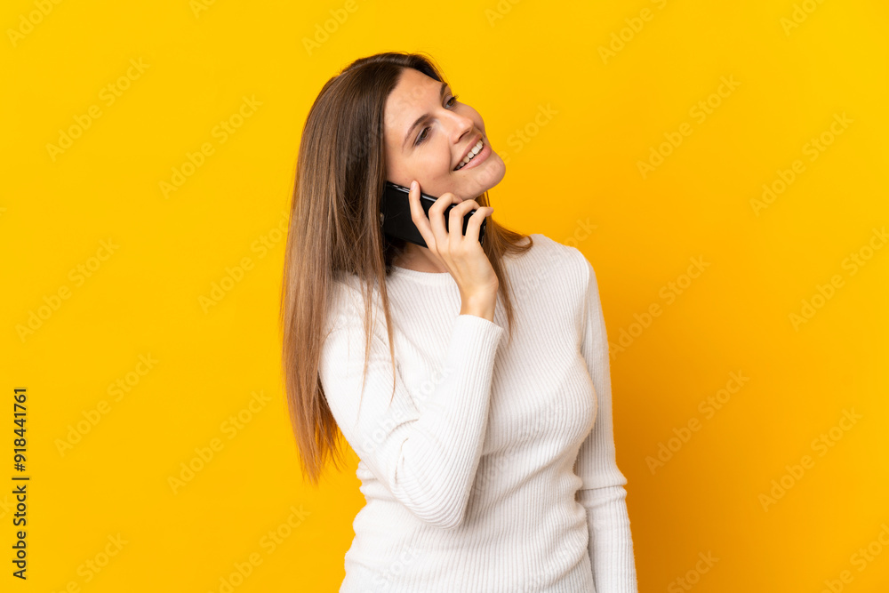 Young Slovak woman isolated on yellow background keeping a conversation with the mobile phone with someone Young Slovak woman isolated on yellow background keeping a conversation with the mobile phone with someone