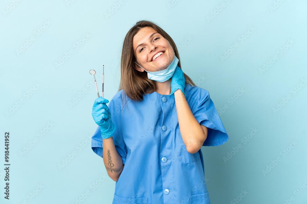 Slovak dentist holding tools isolated on blue background laughing Slovak dentist holding tools isolated on blue background laughing