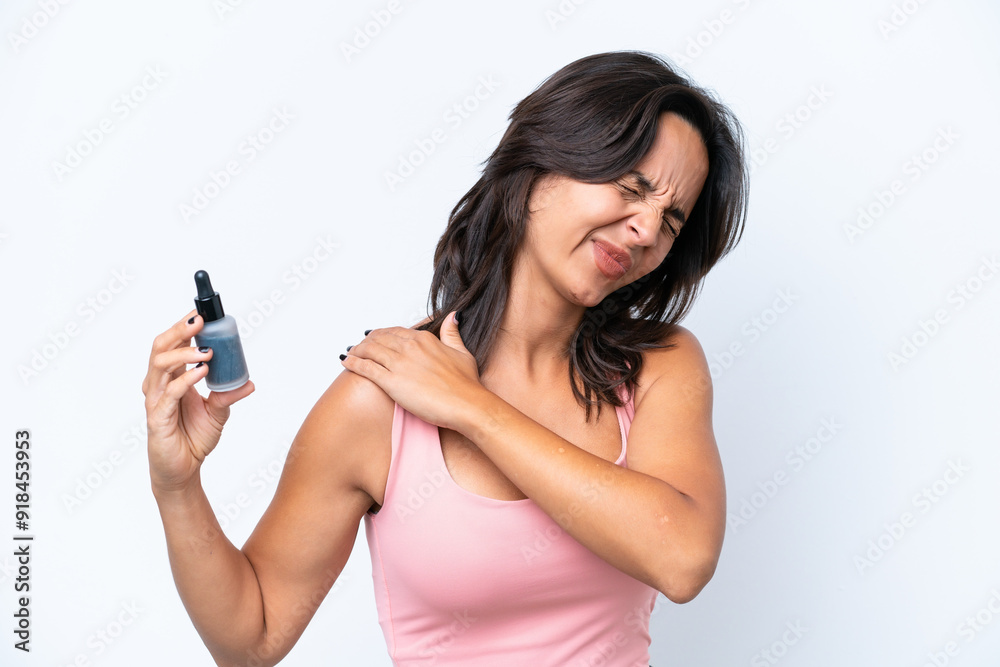 Young hispanic woman holding serum isolated on white background suffering from pain in shoulder for having made an effort Young hispanic woman holding serum isolated on white background suffering from pain in shoulder for having made an effort