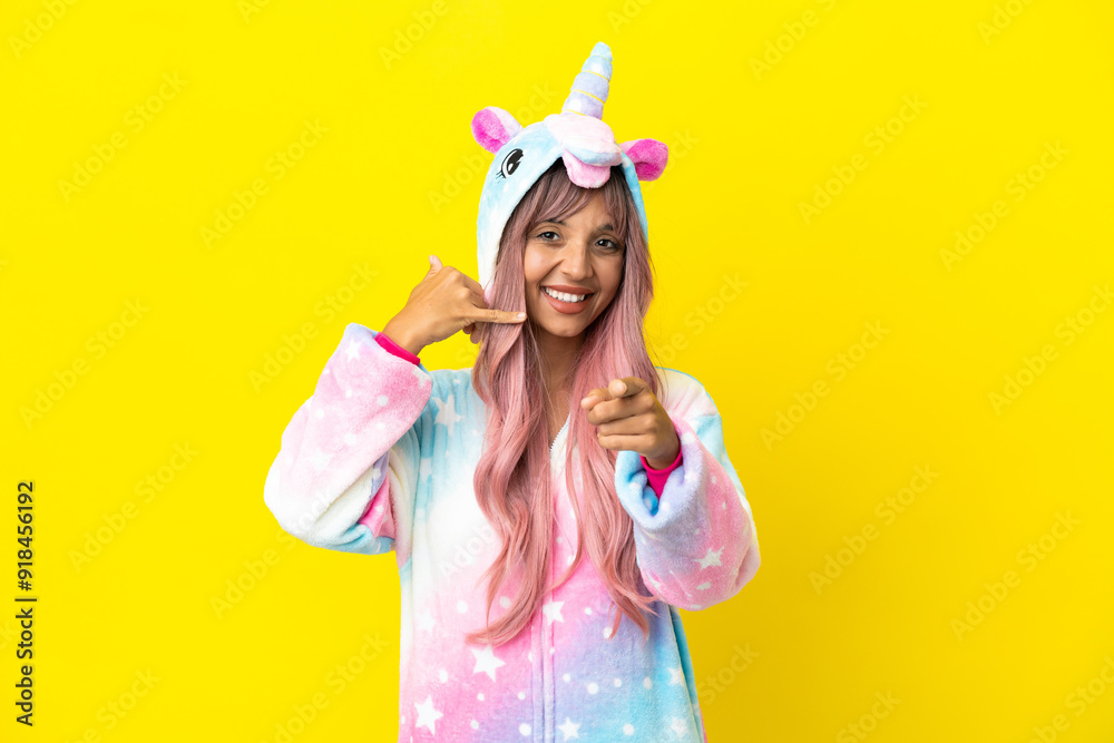 Young mixed race woman wearing a unicorn pajama isolated on white background making phone gesture and pointing front Young mixed race woman wearing a unicorn pajama isolated on white background making phone gesture and pointing front