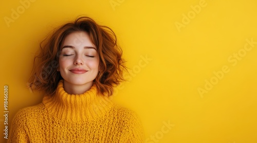 A woman appears content as she relaxes in a yellow sweater against a matching yellow background. Her calm demeanor and the monochromatic palette create a cohesive image. photo