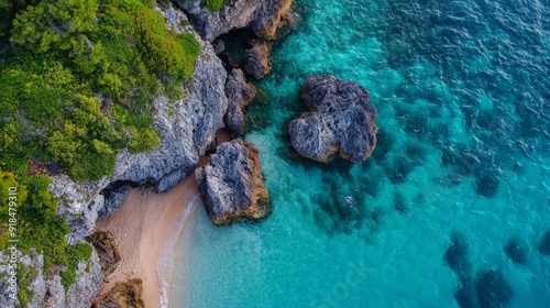  A bird's-eye perspective of a sandy shore adjoining a body of water, featuring a rocky formation midway photo