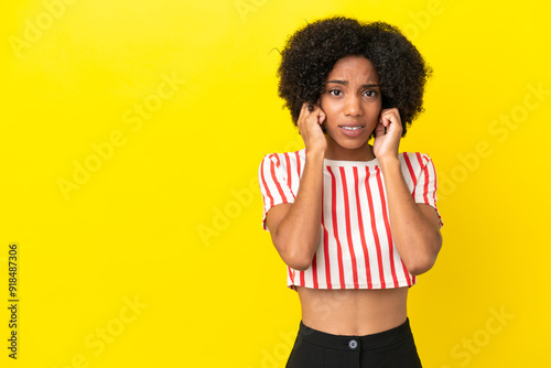 Young African American woman isolated on yellow background frustrated and covering ears