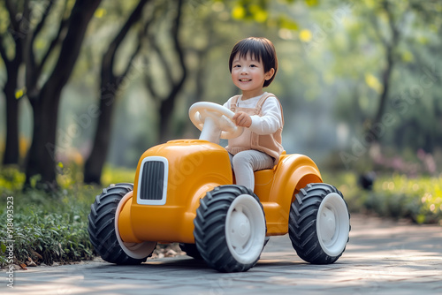 Happy Toddler Riding Orange Toy Tractor in Park, Playful Outdoor Adventure photo