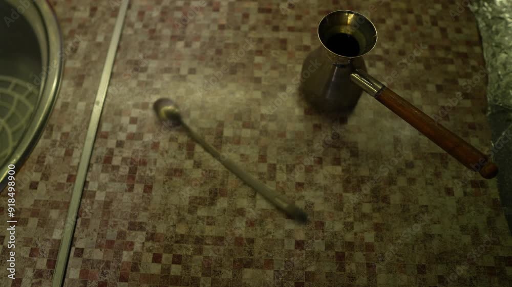 Closeup view of kitchen worktop with standing jezve and rotating dessert spoon filmed in slow motion. Top footage of home utensil ready to prepare aroma arabica beverage. Cooking drink at home