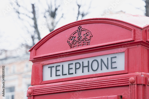 classic red telephone cabin foreground object and blurred neutral color gray day background