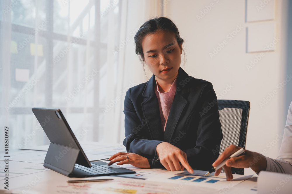 Focused businesswoman analyzes charts on her desk using a digital tablet in a bright office setting, embodying teamwork and collaboration in a corporate environment Focused businesswoman analyzes charts on her desk using a digital tablet in a bright office setting, embodying teamwork and collaboration in a corporate environment