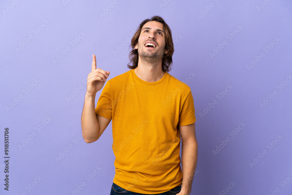 Young handsome man isolated on purple background pointing up and surprised Young handsome man isolated on purple background pointing up and surprised