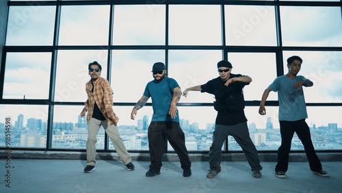 Group of multicultural dancer dancing together with skyscraper. Portrait of multicultural hipster team moving foot step with confident near window with urban city view. Outdoor sport 2024. Hiphop.