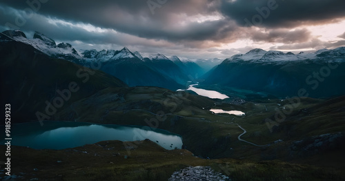 Dramatic sunset illuminating snow capped mountain range with winding road and lakes photo