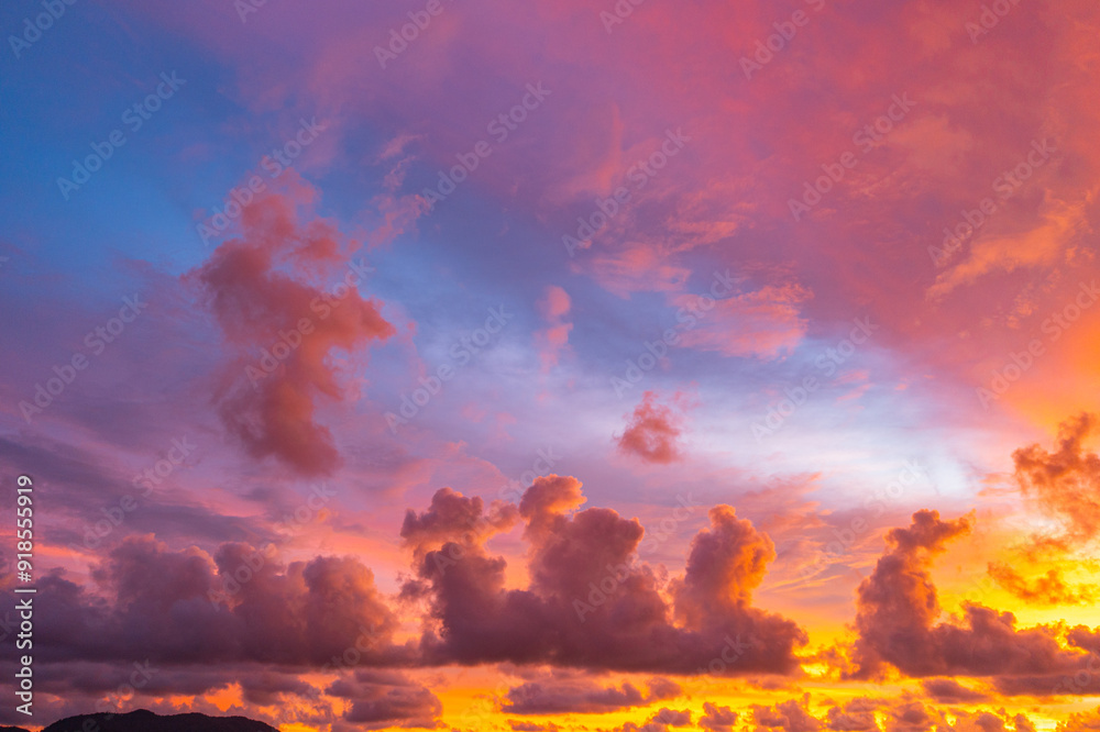 Fototapeta premium .The sky is painted with hues of deep orange, red, and pink, gradually blending into shades of purple and blue. The clouds reflect these vibrant colors, creating a breathtaking and serene landscape.