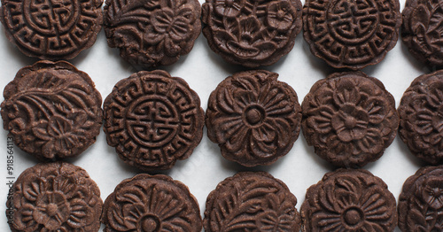 Overhead view of stamped chocolate cookies on a parchment lined baking tray, top view of embossed chocolate sugar cookies on a white background