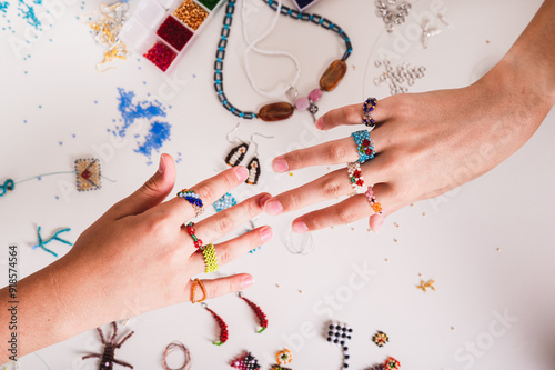 Bilde på lerret Children's hands showing beaded rings above work table top view
