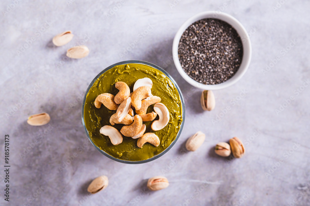 Fototapeta premium Close up of organic chia pudding with pistachio butter and cashews in a glass on top view