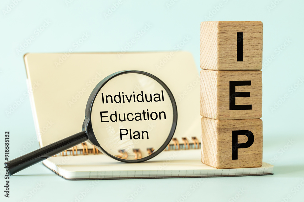 Individual Education Plan IEP symbol. Business concept, IEP 504 program, text on natural wooden block placed next to open school notebook and magnifying glass. copy space. Pastel blue background
