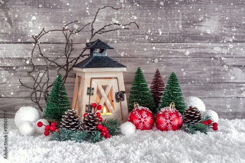 A Christmas lantern, a Christmas tree, pine cones and red balls on the snow are decorated with tinsel.  Christmas and New Year decorations. photo