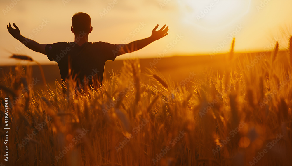Silhouette of Man with hands up standing in wheat field. Beautiful Nature Sunset Landscape. Rural Scenery under Shining Sunlight. Background of ripening ears of wheat field. Rich harvest Concept Silhouette of Man with hands up standing in wheat field. Beautiful Nature Sunset Landscape. Rural Scenery under Shining Sunlight. Background of ripening ears of wheat field. Rich harvest Concept