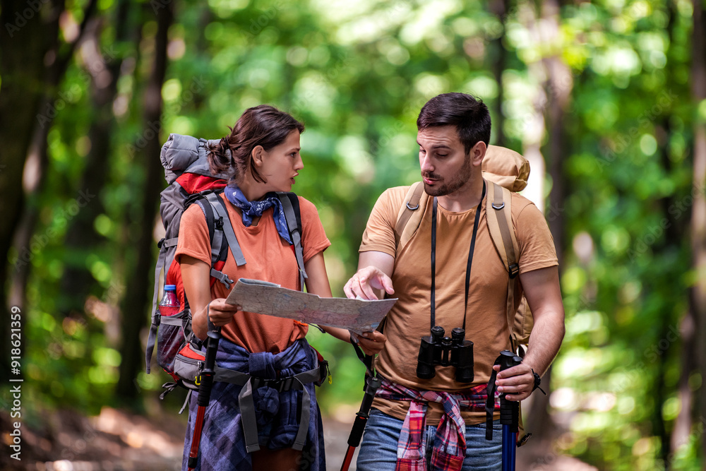 Hiker couple in the forest using map Hiker couple in the forest using map