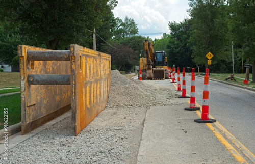 A trench box for laying pipe in a water line replacement and backhoe in a road construction zone