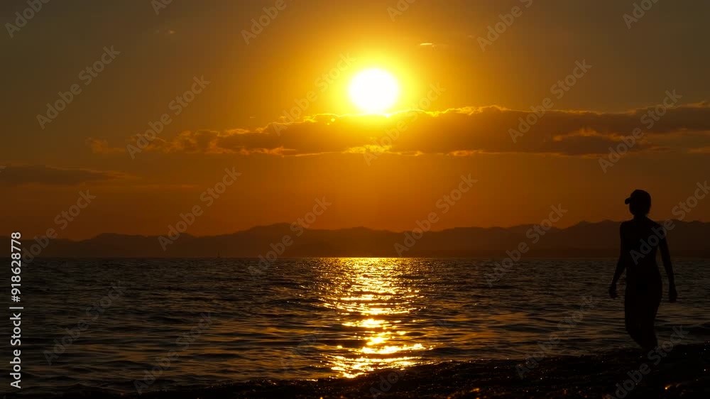 Resting female on pebbles against sunset. A resting traveler woman in swimsuit have an evening promenade on the bay. Resting female on pebbles against sunset. A resting traveler woman in swimsuit have an evening promenade on the bay.