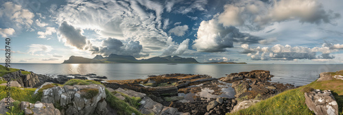 Dramatic Coastal View of Eigg Island with Rocky Shoreline and Cloud-Filled Sky photo