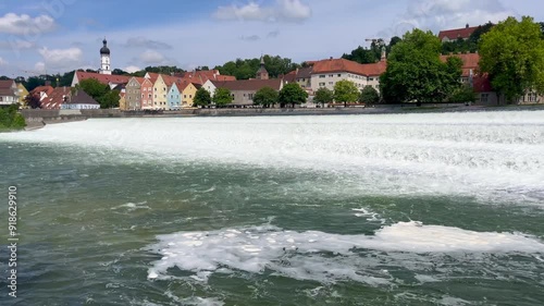 Panoramic view of the picturesque town of Landsberg am Lech, Germany, with colorful houses and a scenic water cascade on the Lech River