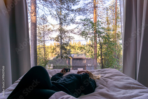 blonde woman looking through the window on the forest  in Rovaniemi Finland in summer time photo