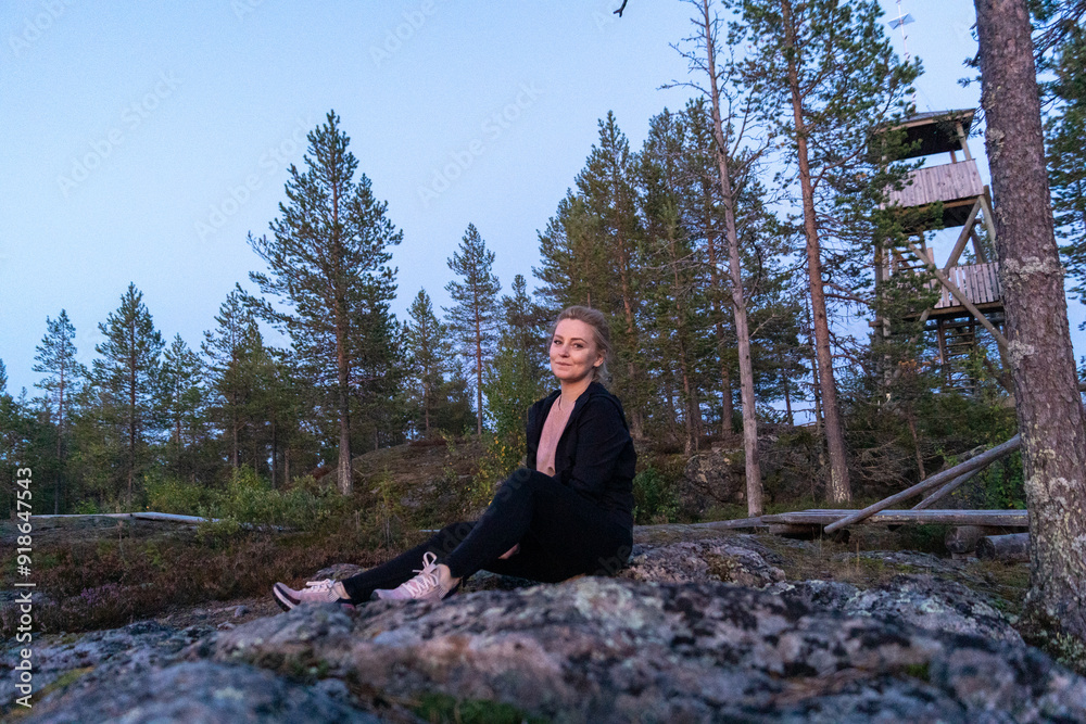 Fototapeta premium blonde woman hiking in the forest in Rovaniemi Finland Lapland, on a white night in summer with sunset