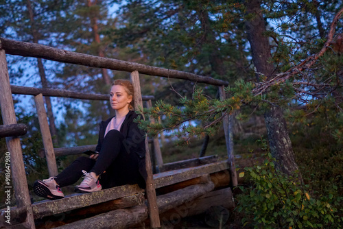 blonde woman hiking in the forest in Rovaniemi Finland Lapland, on a white night in summer with sunset