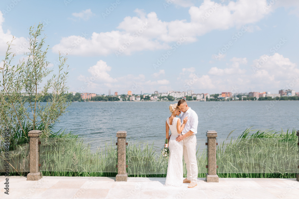 Romantic Wedding Couple Embracing by the Lake on a Sunny Day Romantic Wedding Couple Embracing by the Lake on a Sunny Day